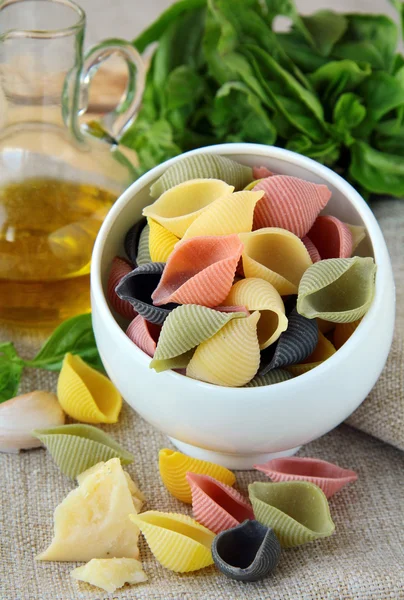 Uncooked tricolor pasta in cup with olive oil — Stock Photo, Image