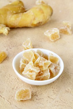 Candied ginger and fresh ginger on a beige background clipart