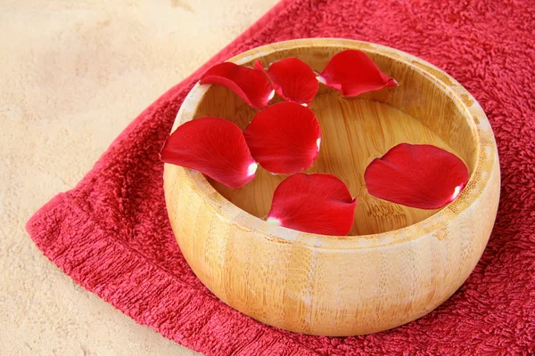 Conceito de spa com pétalas de rosa e uma toalha vermelha — Fotografia de Stock