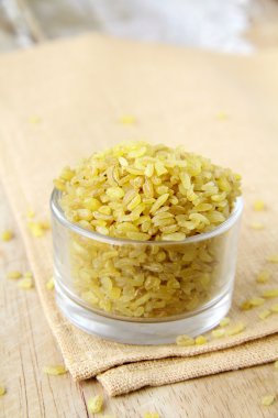 Bulgur wheat in a glass bowl on a wooden table clipart