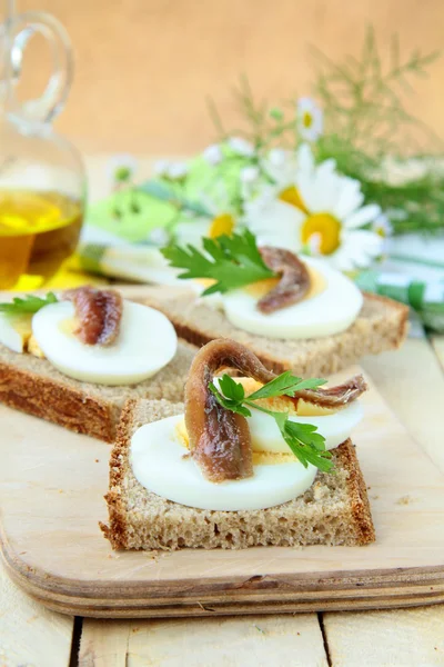 Bocadillos de bocadillos con huevo y anchoas en una tabla de madera — Foto de Stock