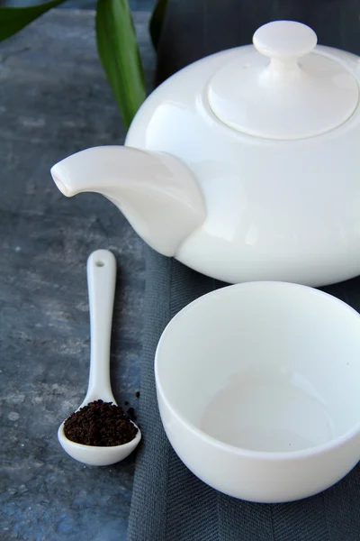 Pequeña taza de té blanco y una tetera sobre fondo gris — Foto de Stock