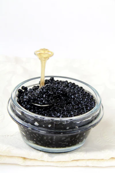 Caviar preto em um frasco de vidro em um fundo branco — Fotografia de Stock
