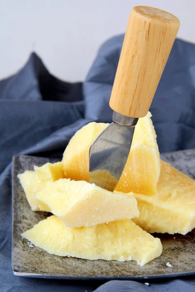 Parmesan cheese on a wooden table with knife — Stock Photo, Image