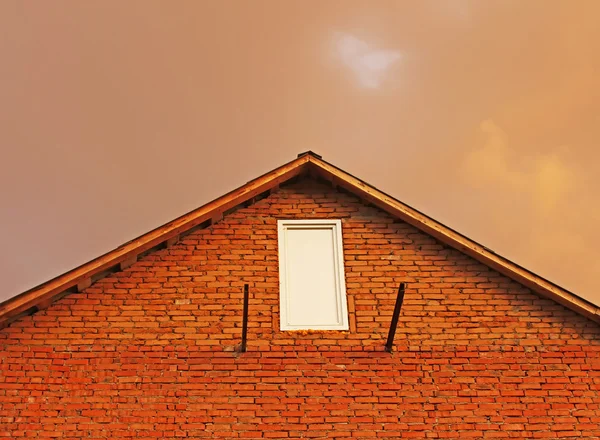 Fragmento de casa de tijolo no fundo nuvens de trovão avermelhadas . — Fotografia de Stock