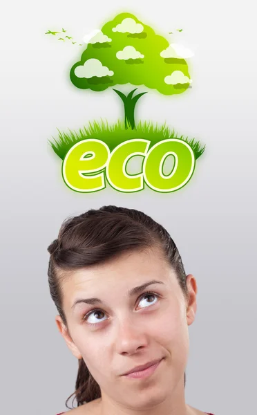 Молодая девушка смотрит на зеленый экологический знак — стоковое фото