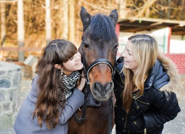 Two girls holding a horse clipart