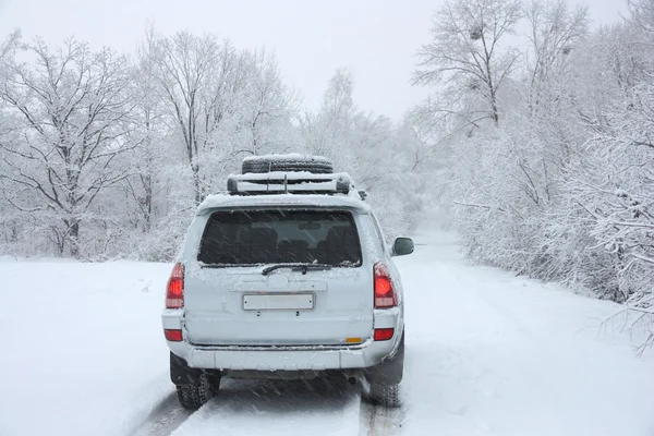 Śnieżna zimowa droga za nierozpoznawalnym samochodem — Zdjęcie stockowe