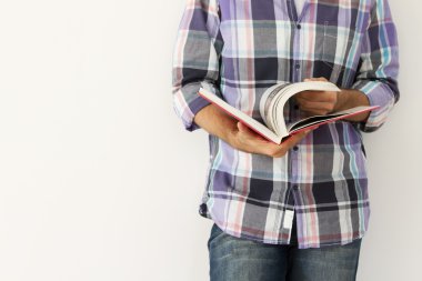 Young man against the wall reading a book clipart