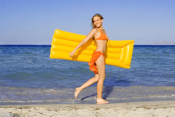 Happy young woman walking on beach with airbed on summer vacation — Stock Photo, Image