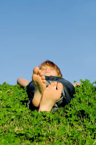 Kind ontspannen buitenshuis, focus op voeten. — Stockfoto