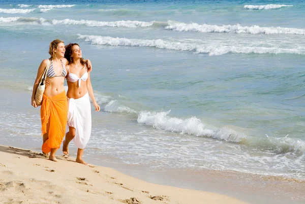 Junge Frauen, die im Sommerurlaub oder Frühjahrspause am Strand entlang spazieren — Stockfoto
