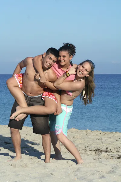 Sorrindo grupo de jovens, crianças, ou adolescentes brincando, piggyback na praia summe — Fotografia de Stock