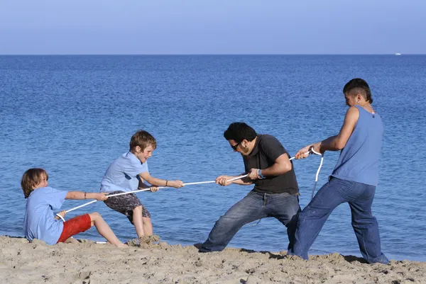 拔河游戏，小孩子在玩耍时在海滩上不公平的优势 — 图库照片
