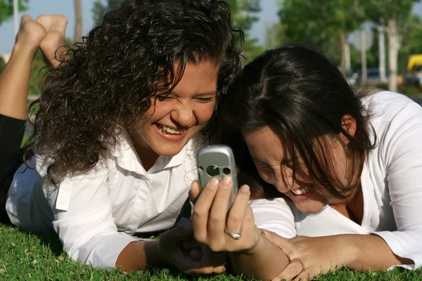 Estudiantes en el campus con teléfono móvil o celular riendo y divirtiéndose —  Fotos de Stock