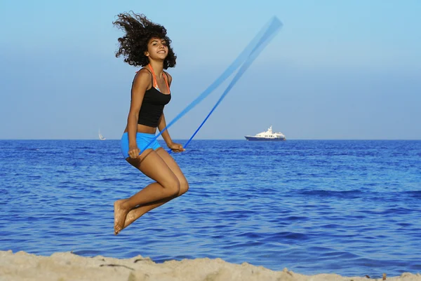 Gesunde Frau hüpft im Sommerurlaub am Strand — Stockfoto