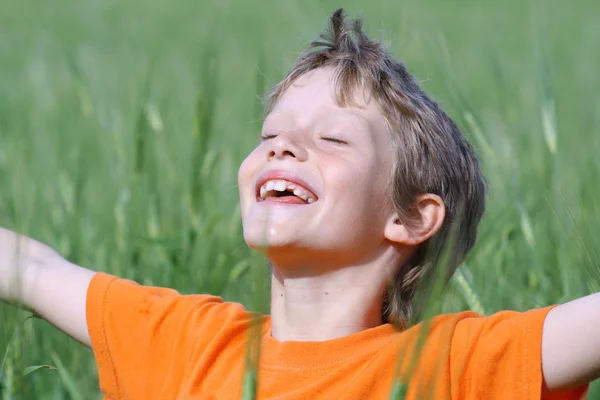 Felice bambino sorridente braccia distese gli occhi chiusi godendo il sole estivo — Foto Stock