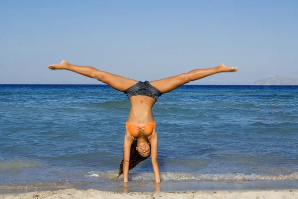 Šťastná žena, která dělá přemet stranou nebo stojka na letní dovolenou na pláži v mallorc — Stock fotografie