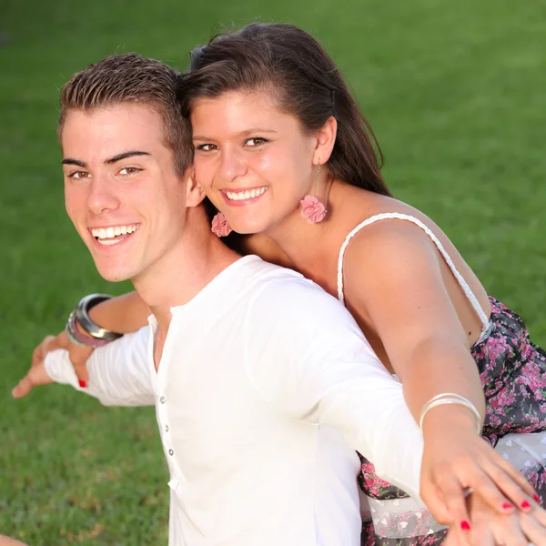Lyckliga piggyback paret med perfekta leenden — Stockfoto