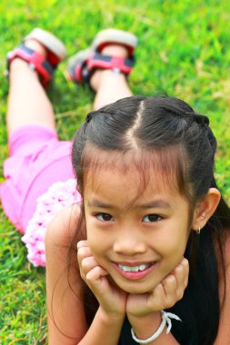 Asian girl lying in the grass clipart