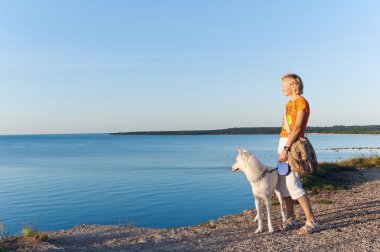 The woman with a dog costs on edge of breakage at the sea clipart