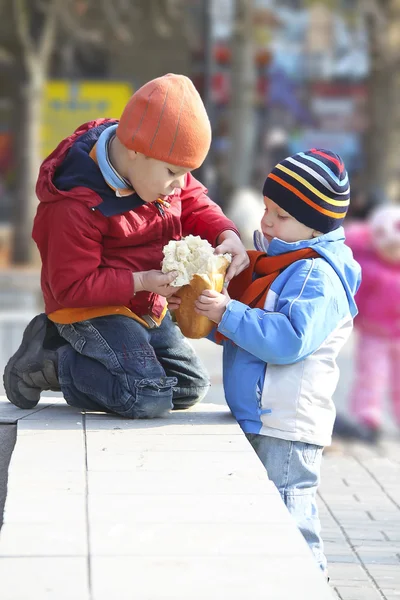 Os irmãos compartilham o pão para um passeio no parque de outono — Fotografia de Stock