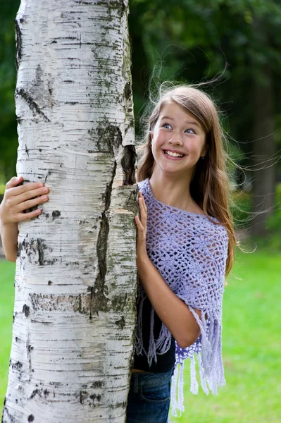 stock image Young girl looks out from the tree