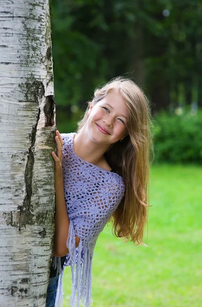 Young girl looks out from the tree — Stock Photo, Image