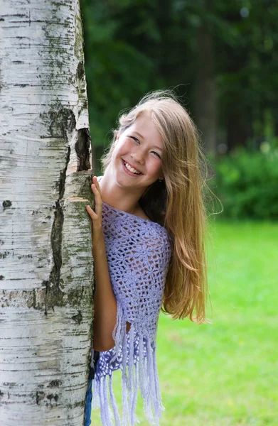 Jong meisje kijkt uit van de boom — Stockfoto