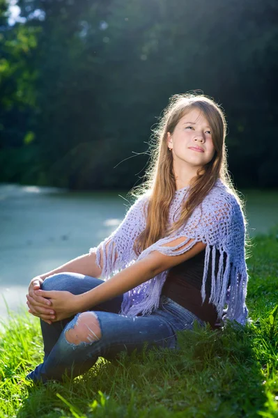 日差しの中で草の上に座っているきれいな女の子 — Stock fotografie
