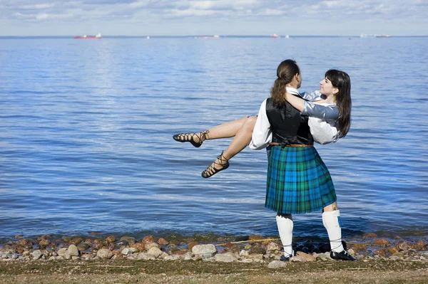Чоловік у шотландському костюмі тримає жінку — стокове фото