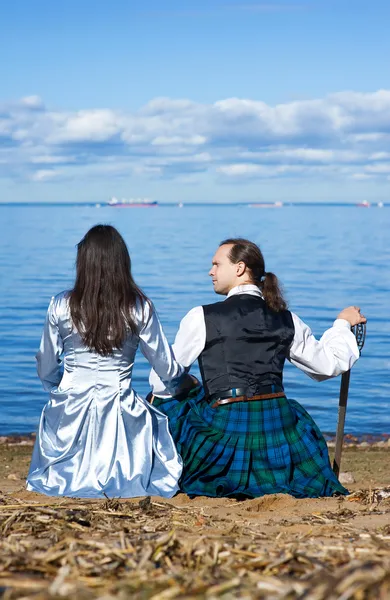 Kvinna och man i skotsk dräkt nära havet — Stockfoto