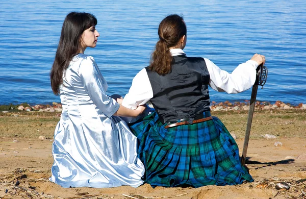 Kvinna och man i skotsk dräkt sitter nära havet — Stockfoto
