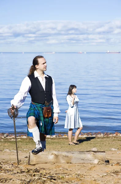 Мужчина в шотландском костюме и женщина у моря — стоковое фото