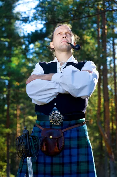 Homem de traje escocês com espada e cachimbo — Fotografia de Stock
