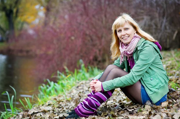 川の土手に座っている金髪の女性 — ストック写真