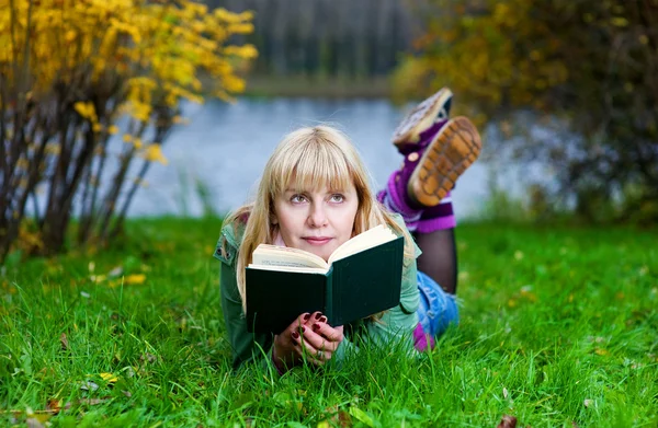 Женщина, читающая книгу на траве — стоковое фото