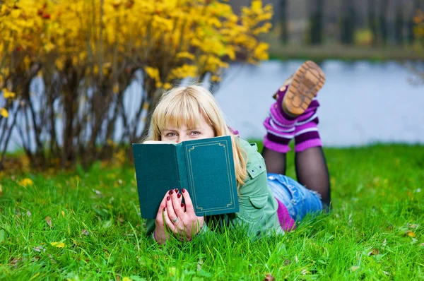 Donna con libro sdraiata sull'erba — Foto Stock