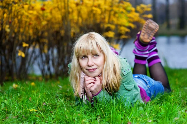 Mulher loira em polainas deitada na grama — Fotografia de Stock