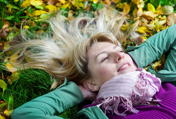 Blond kvinna i halsduk liggande i gräset — Stockfoto