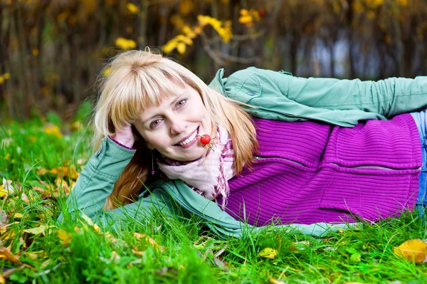 Mulher deitada na grama com baga na boca — Fotografia de Stock