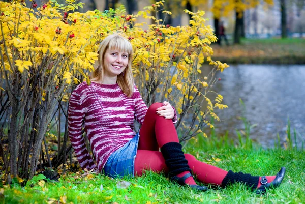 Smiling woman sitting on the river bank — Stock Photo, Image