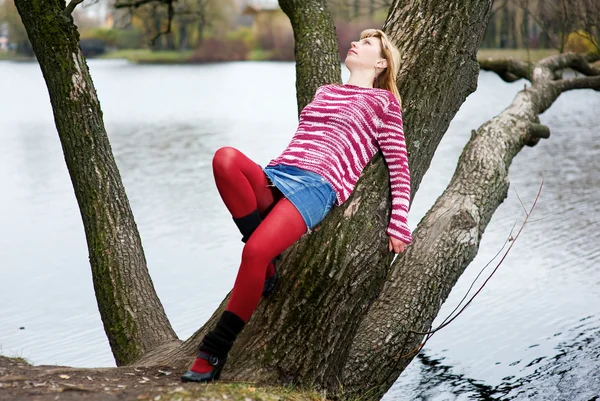 Szőke nő feküdt a fa piros harisnya — Stock Fotó