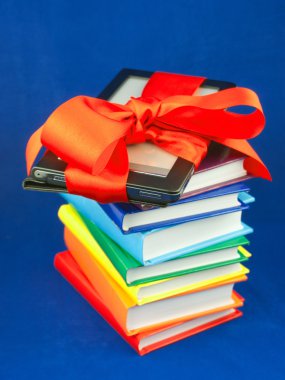 Electronic book reader tied up with red ribbon on the stack of books clipart