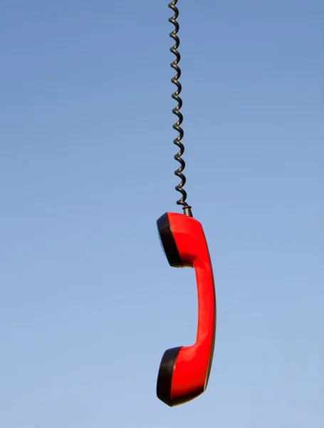 Czerwony telefon słuchawki wiszące przeciw błękitne niebo — Zdjęcie stockowe