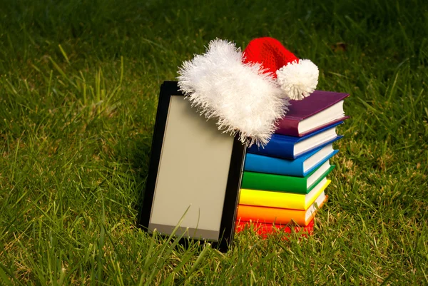 Электронный читатель книг в шляпе Санты со стопкой книг — стоковое фото