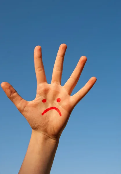 Il palmo della mano umana con un sorriso infelice disegnato su di esso — Foto Stock