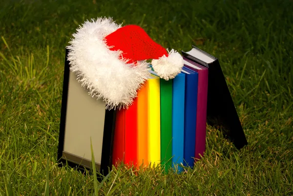 Lecteur de livres électroniques portant le chapeau du Père Noël avec une rangée de livres — Photo
