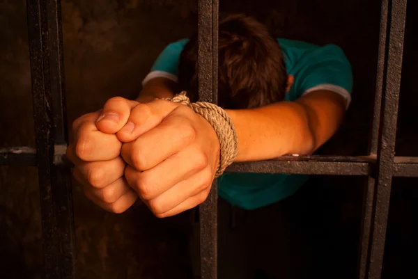 Man with hands tied with rope behind the bars — Stock Photo, Image