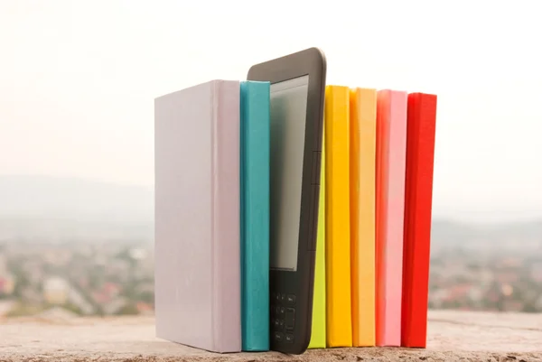 Ряд красочных книг с электронным читателем — стоковое фото